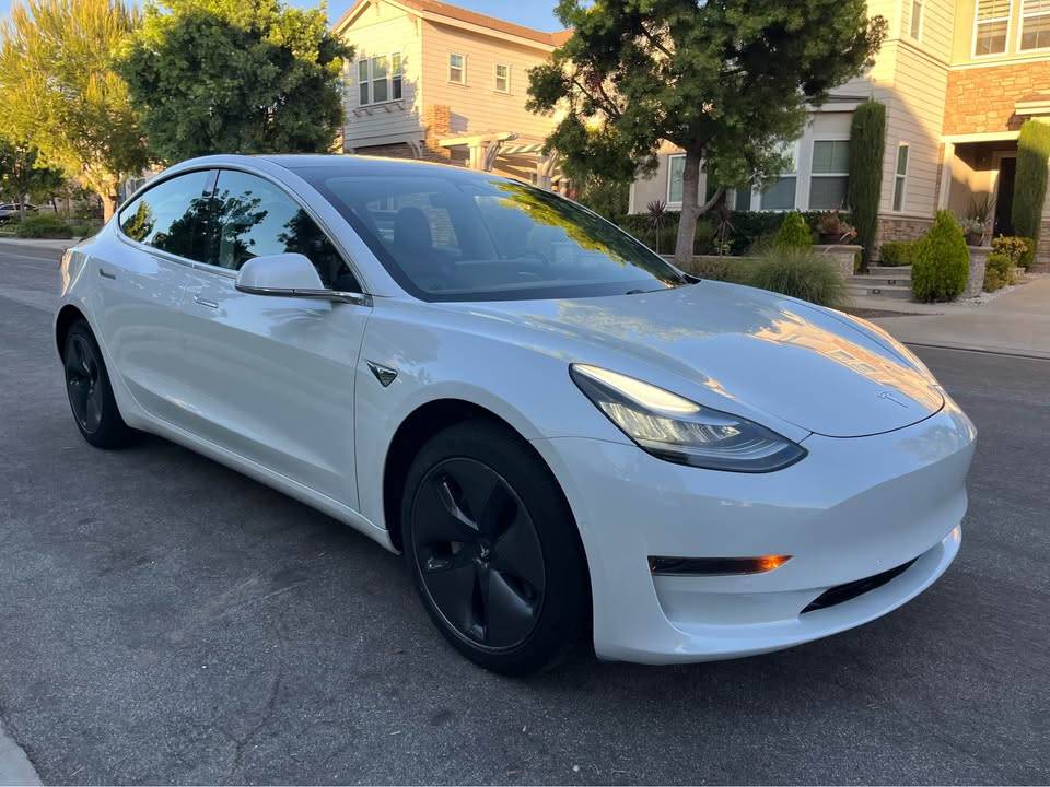 A white Tesla Model 3 parked in a driveway